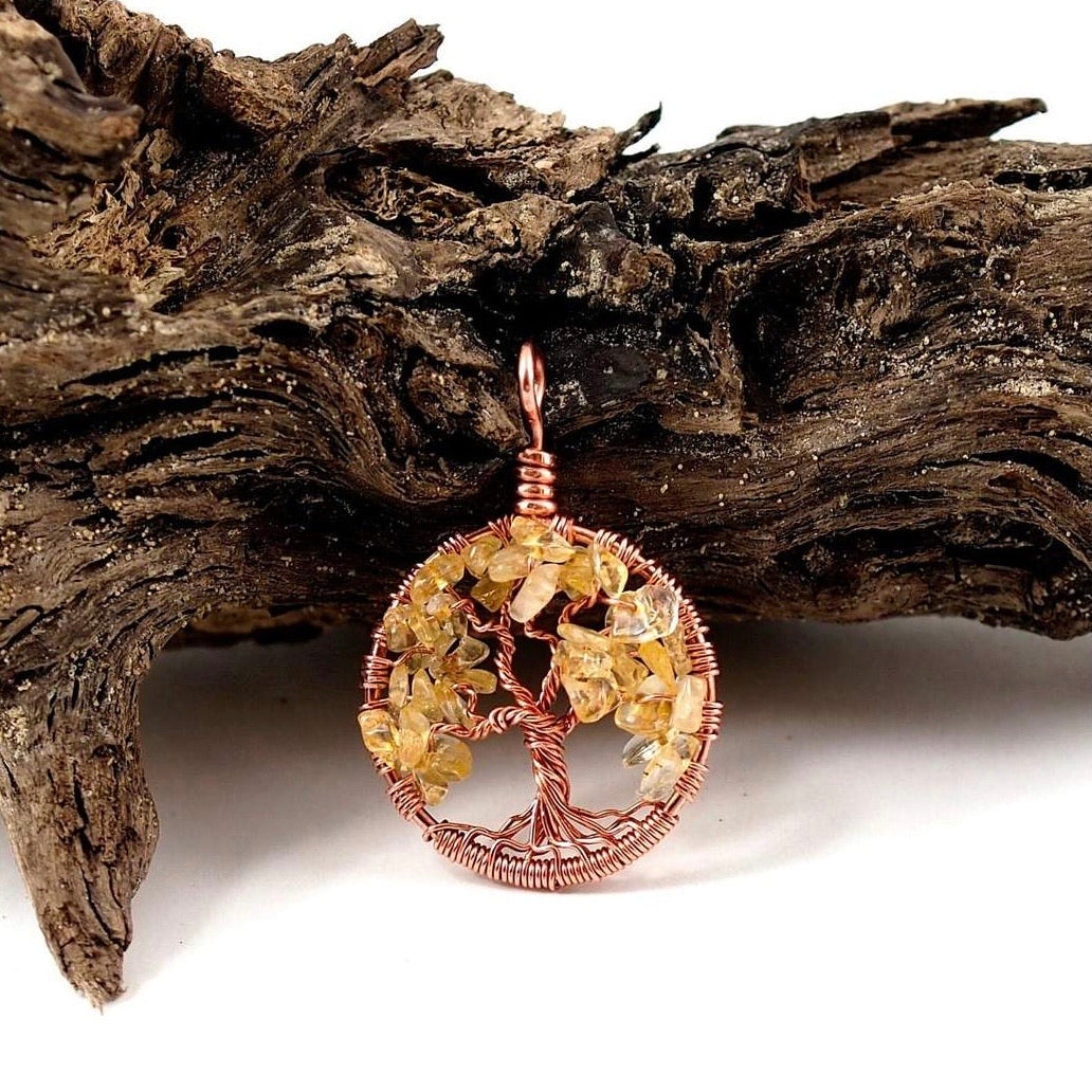 A product image of the November birthstone tree of life pendant from Uncorked & Bottled Up made with genuine citrine gemstones and copper wire against a wood background
