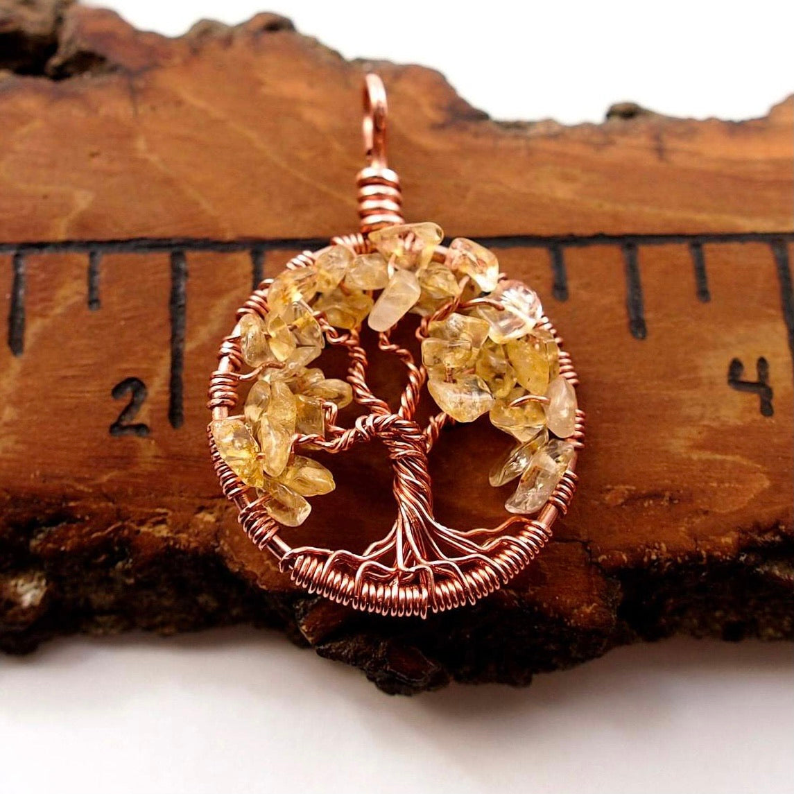 An image of the November birthstone tree of life pendant from Uncorked & Bottled Up on a ruler to show product size. Made with genuine citrine gemstones and copper wire